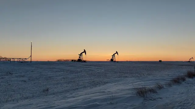 Pumpjacks at dusk over snowy fields