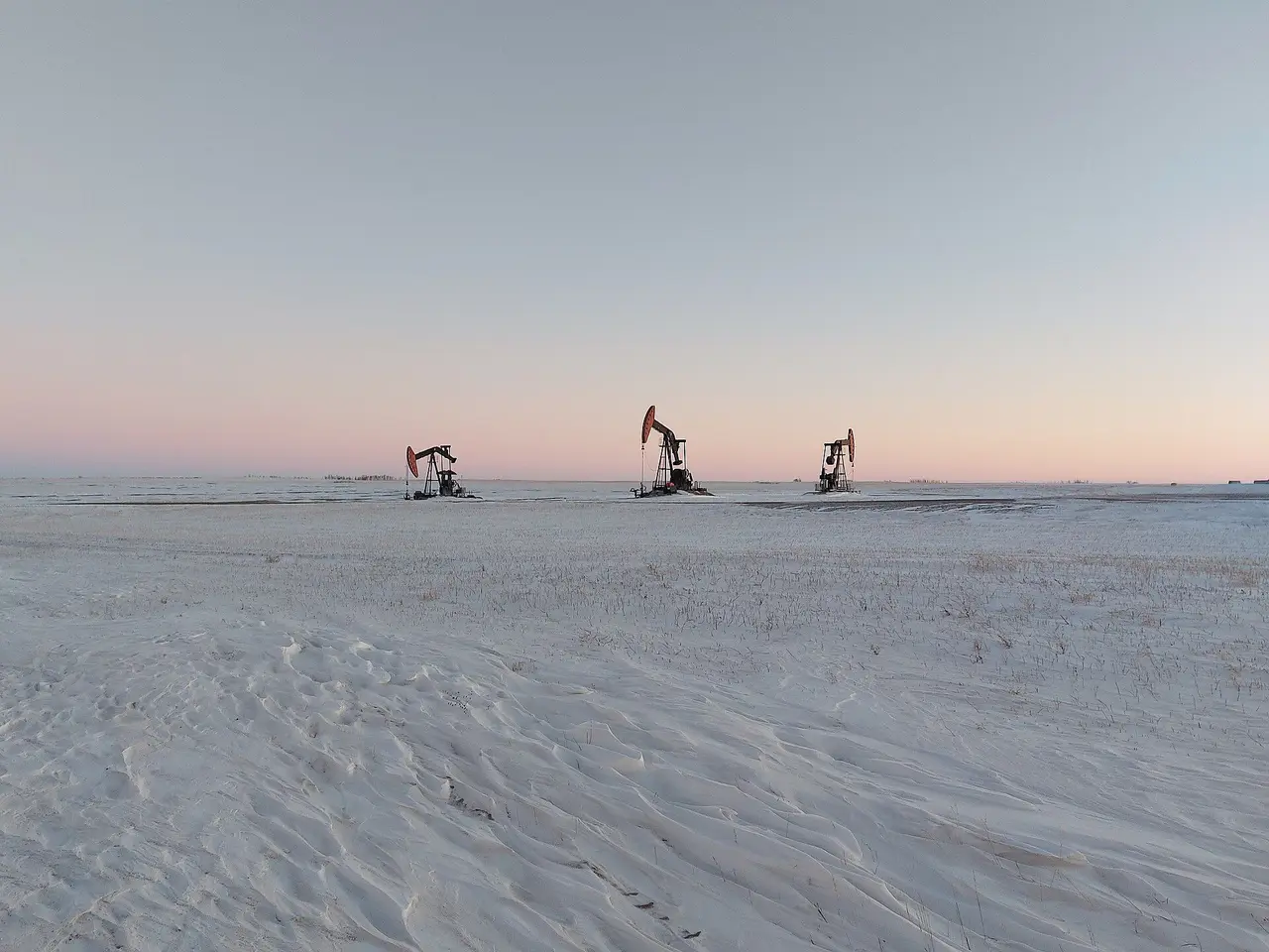 Pumpjacks on the snowy prairie at dusk, 2022
