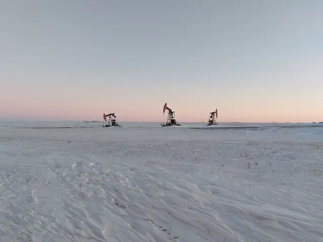 Pumpjacks on the snowy prairie at dusk